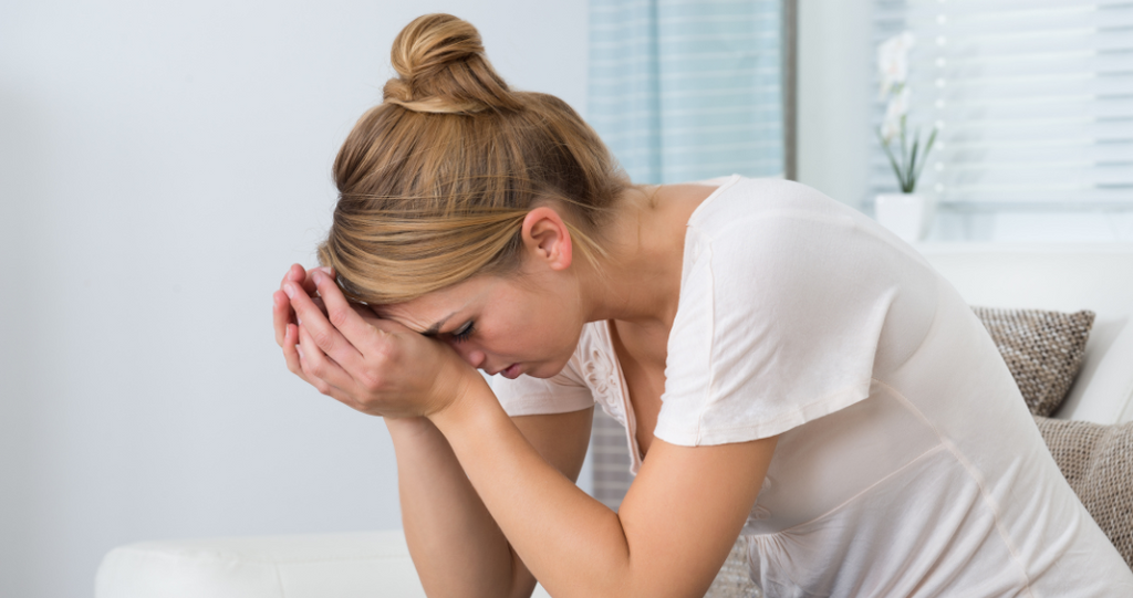Woman holding her head in hands looking stressed and worn out