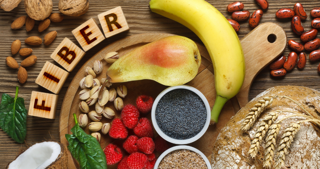 Table filled with fiber-rich foods and letter blocks spelling out the word FIBER