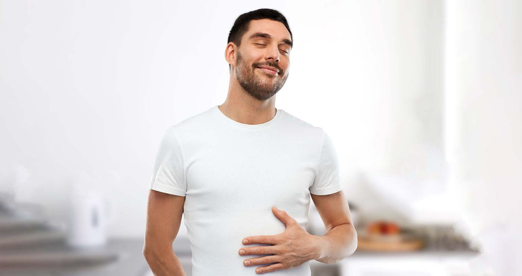 Man smiling with hand in stomach showing digestive comfort 