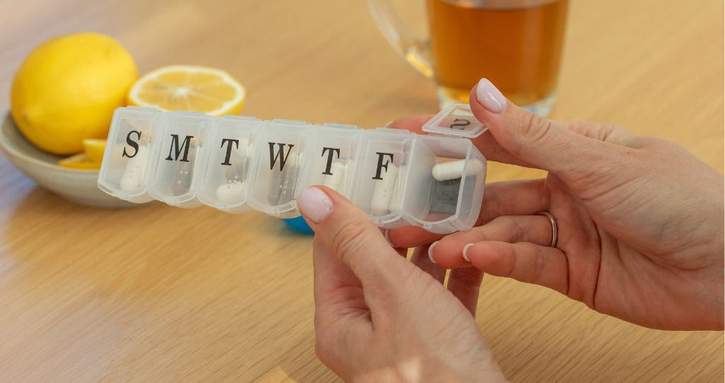 Woman holding pill organizer with supplements inside