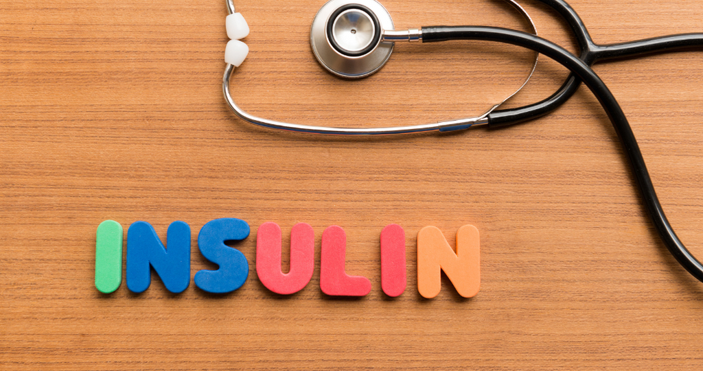 A stethoscope lies on a wooden surface next to colorful letters spelling out 'INSULIN'. This image represents the medical concept of insulin and its role in managing blood sugar levels