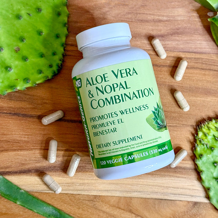 Bottle of aloe vera and nopal cactus supplement laying on wooden surface with aloe vera leaves  and nopal paddles around it